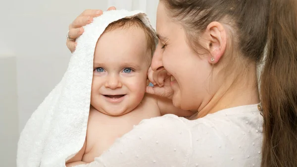 Caring mother wiping and drying her baby son with towel after washing in bath. Concept of children hygiene, healthcare and family care at home