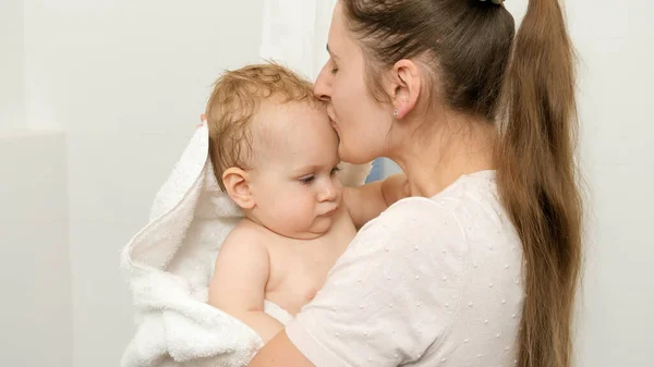 Madre cariñosa besando a su hijo bebé después de lavarse en el baño — Foto de Stock