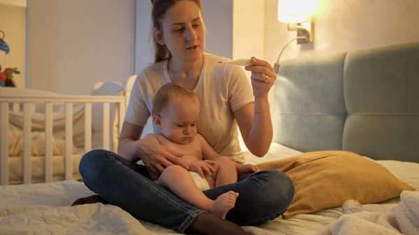 Madre midiendo la temperatura corporal de sus hijos por la noche. Niño enfermo en casa —  Fotos de Stock