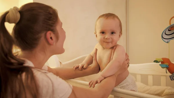 Retrato de adorbale sorrindo menino em fraldas de pé na cama à noite — Fotografia de Stock