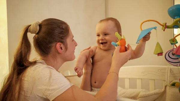 Portrét šťastného smějícího se chlapečka s matkou hrající a bavící se v dětské postýlce v noci — Stock fotografie