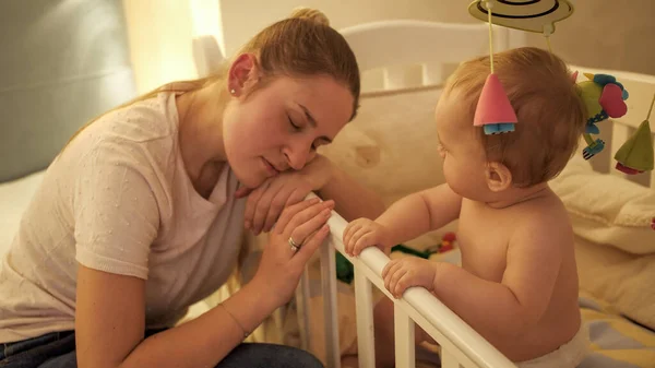 Portret zmęczonej matki opierającej się na łóżku i śpiącej obok synka — Zdjęcie stockowe