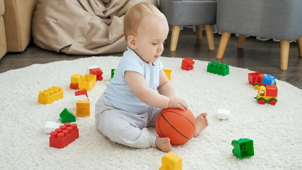 Cute little boy gry zabawki i odbijając piłkę na dywanie w domu — Zdjęcie stockowe