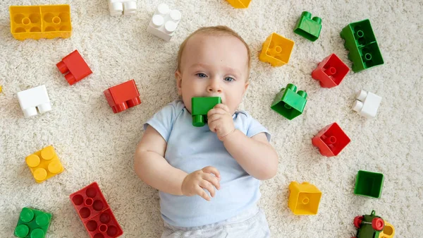 Porträtt av liten pojke tugga och bita färgglada leksaker medan hans tänder växer. Begreppet barns utveckling, utbildning och kreativitet i hemmet — Stockfoto