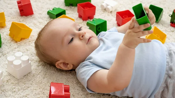 Portret uroczego chłopczyka bawiącego się zabawkami na dywanie w palyroom. Koncepcja rozwoju, edukacji i kreatywności dzieci w domu — Zdjęcie stockowe