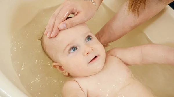 Retrato de un lindo bebé sonriente disfrutando lavándose y nadando en el baño. Concepto de higiene infantil, atención sanitaria y crianza de los hijos. — Foto de Stock