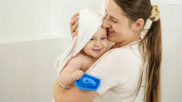 Madre sonriente limpiando a su hijo con toalla después de lavarse en el baño. Concepto de higiene infantil, atención sanitaria y crianza de los hijos. — Foto de Stock