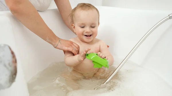 Feliz niño sonriente disfrutando lavándose en el baño y jugando con juguetes. Concepto de higiene infantil, atención sanitaria y desarrollo en el hogar — Foto de Stock