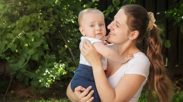 Portrét šťastné usměvavé matky držící a objímající svého malého syna na zahradě. Rodičovství, rodina, vývoj dětí a zábava venku na přírodě. — Stock fotografie