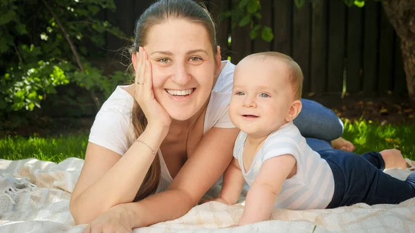 Portret van baby en moeder liggend op een deken op gras in de tuin. Ouderschap, familie, ontwikkeling van kinderen en plezier in de natuur. — Stockfoto