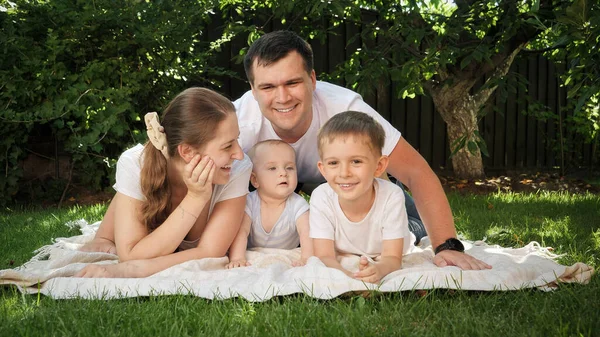 Retrato de familia feliz sonriente relajarse y pasar un buen rato juntos en la hierba en el parque — Foto de Stock