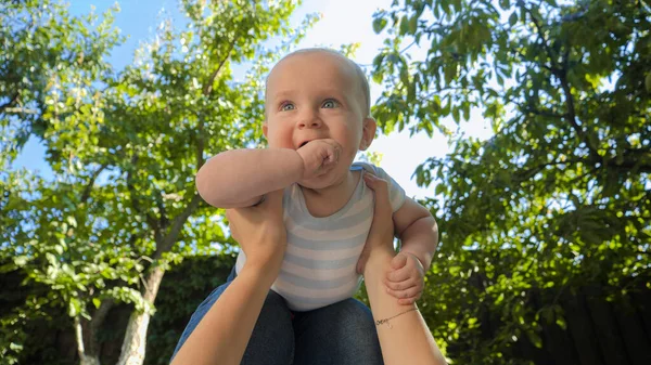 Porträt eines Elternteils hebt niedlichen Jungen vor strahlend blauem Himmel im Park hoch — Stockfoto