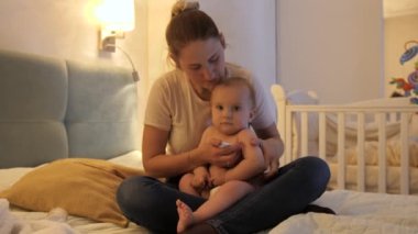Endişeli anne, ağlayan bebeği tutuyor ve termometreyle ısısını ölçüyor. Çocuk sağlığı, ebeveynlik ve çocuk hastalıkları kavramı.