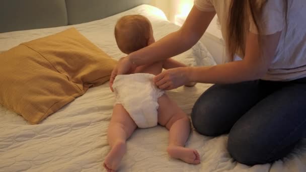 Mãe mudando fraldas usadas bagunçadas para seu filho bebê à noite. Conceito de higiene da criança, cuidados de saúde e cuidados familiares em casa — Vídeo de Stock