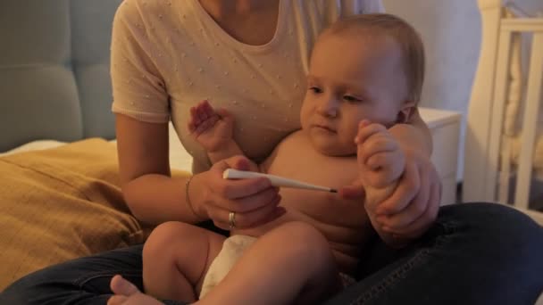 Petit garçon criant et pleurant pendant que sa mère mesurait sa température corporelle avec un thermomètre. Concept de santé infantile, parentalité et maladie infantile. — Video