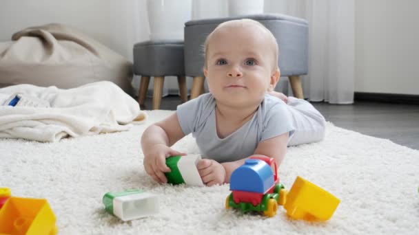 Słodki chłopczyk leżący na dywanie w salonie i uśmiechnięty. Koncepcja rozwoju, edukacji i kreatywności dzieci w domu — Wideo stockowe