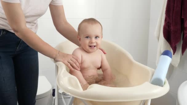 Szczęśliwy uśmiechnięty chłopczyk cieszący się kąpielą. Pojęcie higieny dzieci, opieki zdrowotnej i rodzicielstwa. — Wideo stockowe