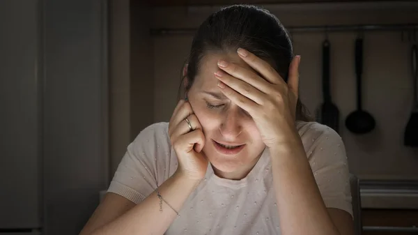 Αναστατωμένη γυναίκα που υποφέρει από κατάθλιψη κλαίγοντας στην κουζίνα τη νύχτα — Φωτογραφία Αρχείου