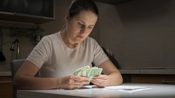 Stresszes és zavarodott nő számolja a pénzét a konyhában éjszaka — Stock Fotó