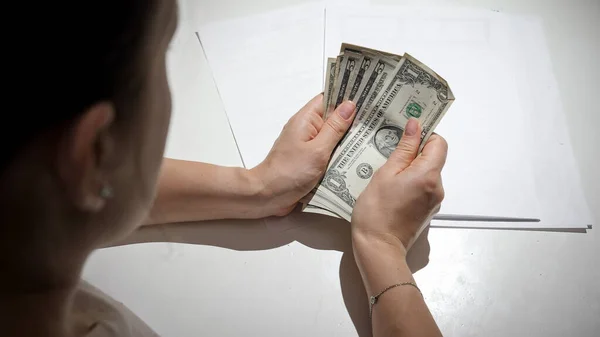CLoseup de jovem mulher com dificuldades financeiras contando seu dinheiro atrás da mesa da cozinha — Fotografia de Stock