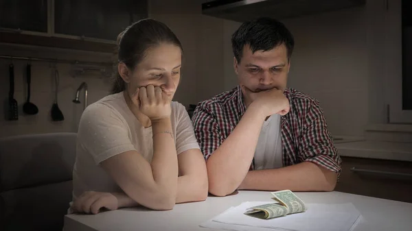 Stressade par sitter i köket på natten och tittar på några pengar sedlar kvar — Stockfoto