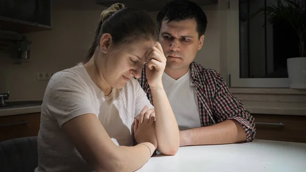 Preocupado jovem olhar para seu choro estressado esposa chorando na cozinha à noite — Fotografia de Stock