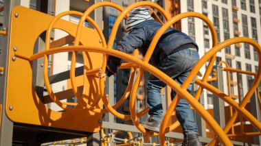 Küçük çocuk, çocuk parkındaki tüp tünelinden modern ev avlusuna tırmanıyor. Çocuk gelişimi, spor ve eğitim kavramı.