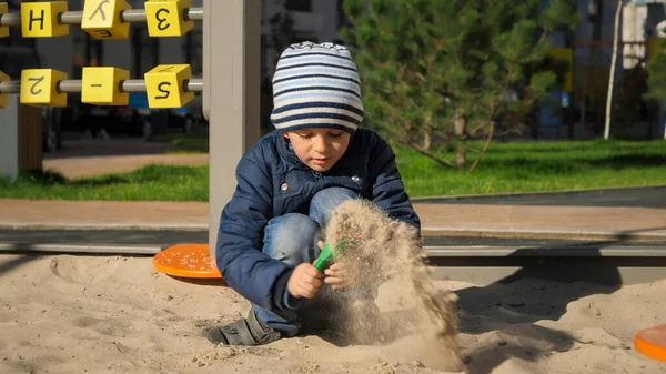 Kleine jongen die zand graaft in een zandbak met een schop op een speelplaats. Concept van kinderontwikkeling, sport en onderwijs. — Stockfoto
