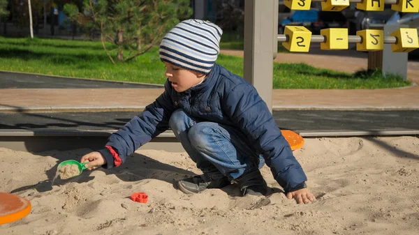 Kleiner Junge spielt im Sandkasten auf dem Palyground und baut eine Sandburg. Konzept der kindlichen Entwicklung, des Sports und der Bildung. — Stockfoto