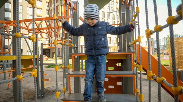 Szczęśliwy uśmiechnięty chłopiec wspinaczka i chodzenie po linach i schodach na placu zabaw dla dzieci. Koncepcja rozwoju dzieci, sportu i edukacji. — Zdjęcie stockowe