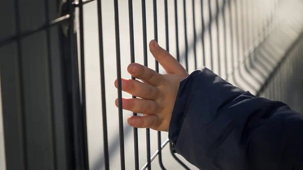Little boy holding metal fence with hands. Concept of poverty, immigration, bullying and kids stress — Stock Photo, Image