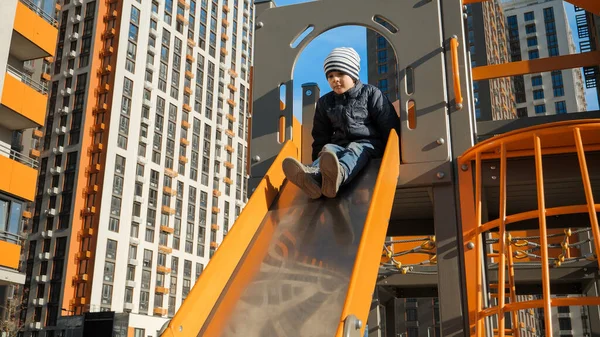 Little boy riding on the metal slide on children palyround at house courtyard. Concept of child development, sports and education. — Stock Photo, Image