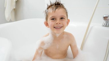 Gülümseyen çocuk banyoda yıkanmayı ve sabun köpüğüyle oynamayı seviyor. Hijyen kavramı, çocuk gelişimi ve evde eğlence