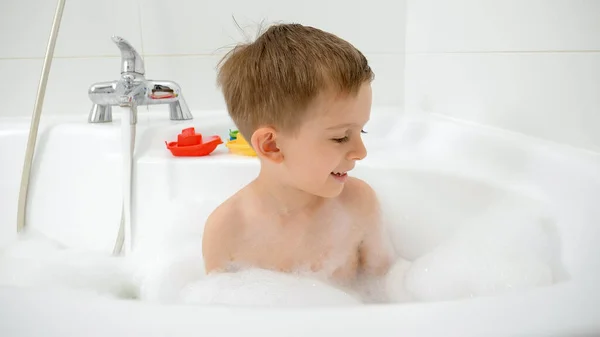 Retrato de un niño pequeño lavándose en un baño lleno de jabón y espuma — Foto de Stock
