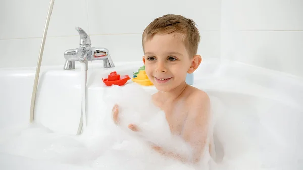 Retrato de niño sonriente feliz tomando baño y sosteniendo un montón de jabón suds y espuma en las manos — Foto de Stock