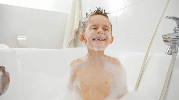 Divertido tiro de niño buceando bajo el agua en baño lleno de espuma de jabón y suds — Foto de Stock