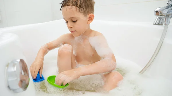 かわいい男の子が風呂で洗濯し、プラスチック製のおもちゃで持っています。家庭での家族の時間、子供の発達と楽しみの概念 — ストック写真