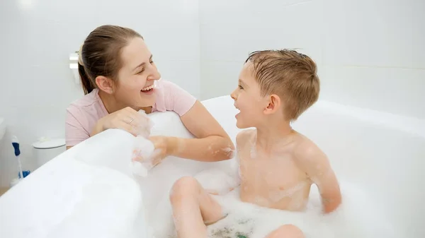 Porträt einer glücklichen Mutter, die ihrem kleinen Sohn beim Waschen im heimischen Bad zulächelt — Stockfoto