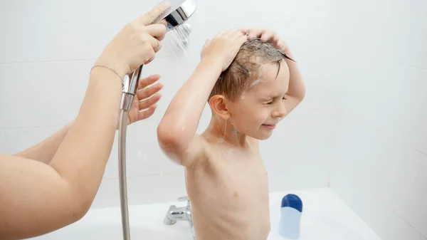 Genç bir anne, küçük oğlunun banyoda duş almasına yardım ediyor. Hijyen kavramı, çocuk gelişimi ve evde eğlence — Stok fotoğraf