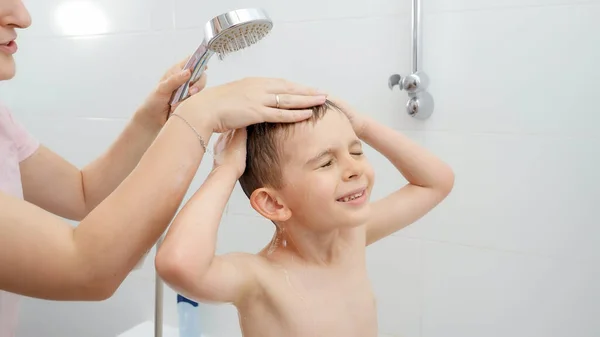 Маленький мальчик с матерью потирает голову и моет волосы шампунем под душем. Концепция гигиены, развития детей и развлечения дома — стоковое фото
