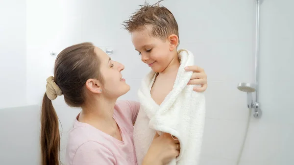 Cuidar a la madre secando a su hijo con toalla y abrazándose después del baño. Concepto de hygine, desarrollo infantil y diversión en casa — Foto de Stock