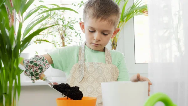 Ritratto di bambino che diffonde terra in vasi colorati per piantare fiori. Concetto di giardinaggio, hobby, piantagione casa. — Foto Stock