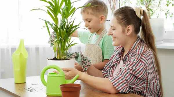 Ritratto di bambino con madre trapiantare fiori in vaso nuovo a casa. Concetto di giardinaggio, hobby, piantagione casa. — Foto Stock