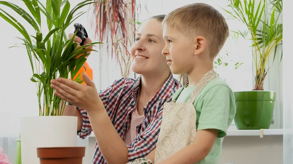 Ragazzino con madre sorridente impianto di irrigazione con irrigatore. Concetto di giardinaggio, hobby, piantagione casa. — Foto Stock