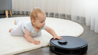 Robot elektrikli süpürgeyle ilgilenen tatlı bir bebek.