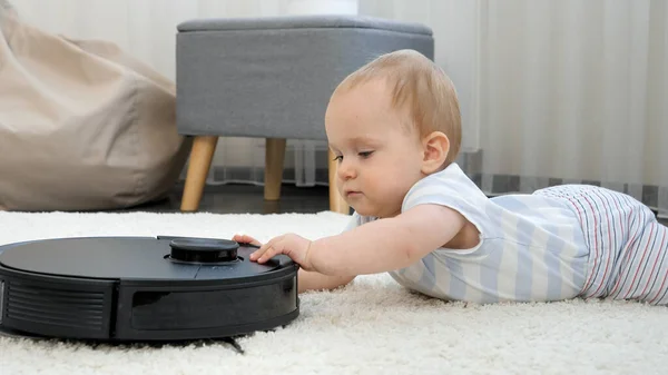 Portret małego chłopca badającego i bawiącego się odkurzaczem robotów. Koncepcja higieny, gadżetów gospodarstwa domowego i robotów we współczesnym życiu. — Zdjęcie stockowe