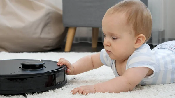 Närbild av liten pojke tittar på roterande borstar av robot dammsugare. Begreppet hygien, hushållsapparater och robotar i det moderna livet. — Stockfoto