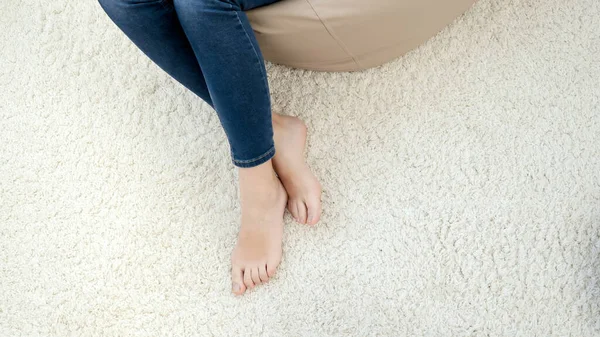 Vista superior de hermosos pies femeninos desnudos acostados en la alfombra blanca suave en casa — Foto de Stock