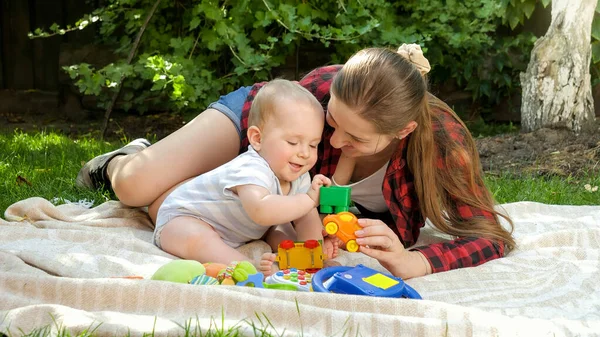 Bonito menino brincando de brinquedos com a jovem mãe no piquenique no jardim — Fotografia de Stock