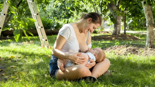 Menino bebê comendo mães leite materno sob macieira no jardim. Conceito de desenvolvimento infantil, família tendo tempo juntos e parentalidade. — Fotografia de Stock
